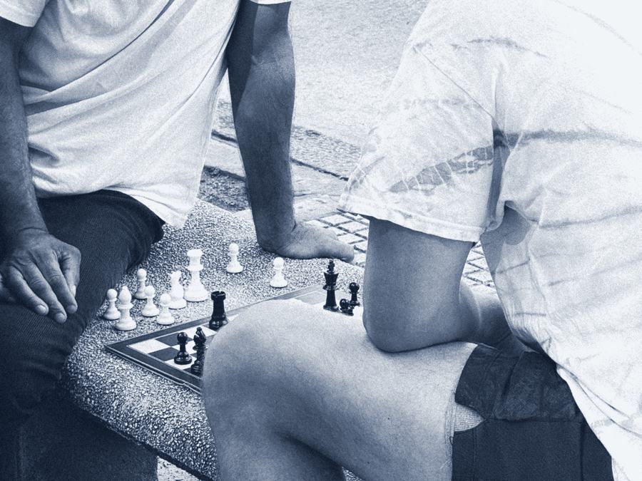 Dos personas jugando al ajedrez en un banco de plaza